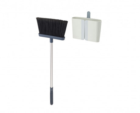 Wall-mounted Joseph Joseph CleanStore Broom with soft bristles, adjustable handle, and a built-in comb for easy cleaning.