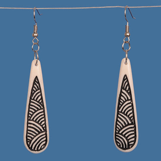 Handcrafted bone drop earrings featuring black patterned stain, inspired by traditional M?ori motifs, showcasing unique elegance.