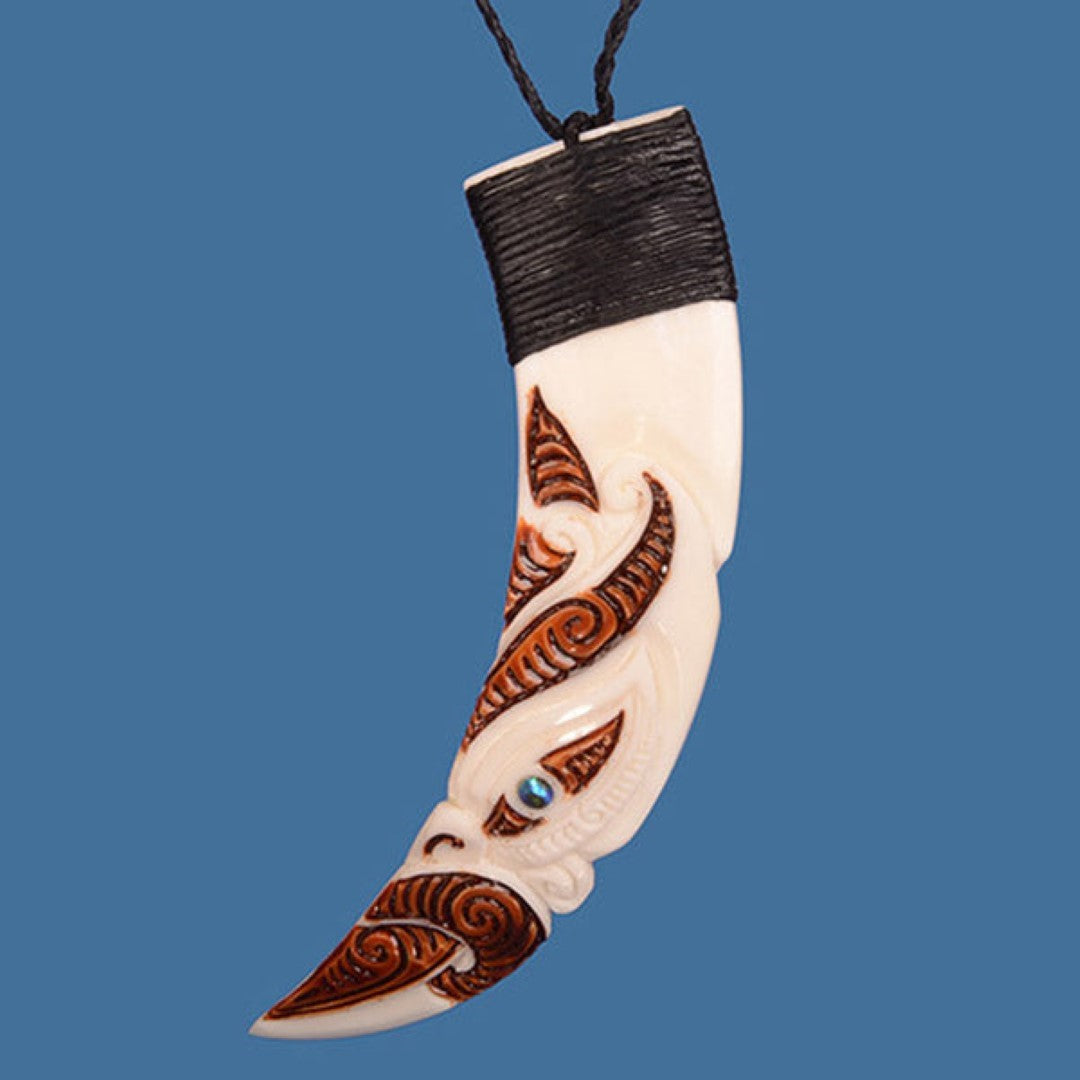 Unique stained pig tusk pendant featuring a Manaia design and P?ua shell eye, displayed on an adjustable braided wax cord.