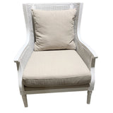 Antique white rattan chair with soft canvas cushion, perfect for cozy living spaces or as a chic accent piece.