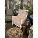 Elegant antique white rattan chair with natural fabric cushion, perfect for stylish relaxation in any living space.