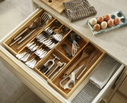 Bamboo drawer organiser with five compartments for cutlery and two for gadgets, expandable for custom storage solutions.