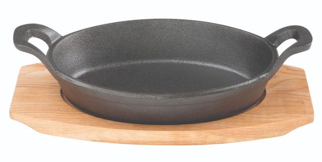 Oval cast iron gratin dish with maple wood tray, perfect for baking and serving a variety of tasty meals.