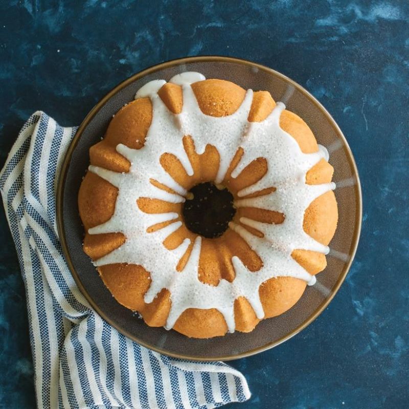 Nordic Ware 12 Cup Bundt Pan in red, crafted from aluminum, features nonstick interior for easy cake release and cleanup.