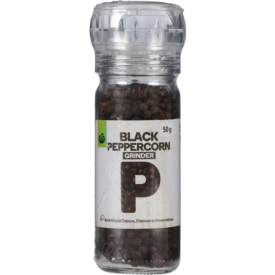 Whole Woolworths Black Peppercorns in a grinder, perfect for enhancing flavor in various dishes without additives.