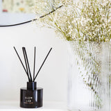 Glow Lab Reed Diffuser in dark glass, featuring warm Vanilla and Forest Berry scents for a cozy home ambiance.