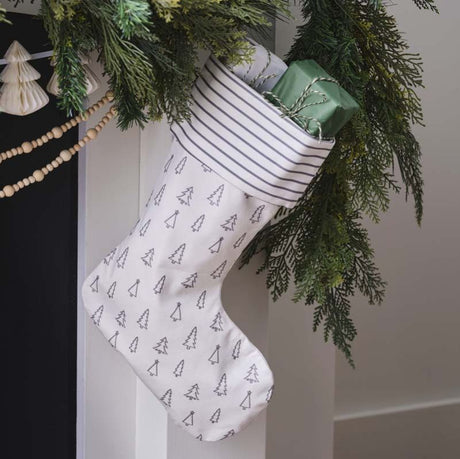 Grey Christmas stocking featuring elegant tree design and stripes, perfect for holding gifts by the fireplace.