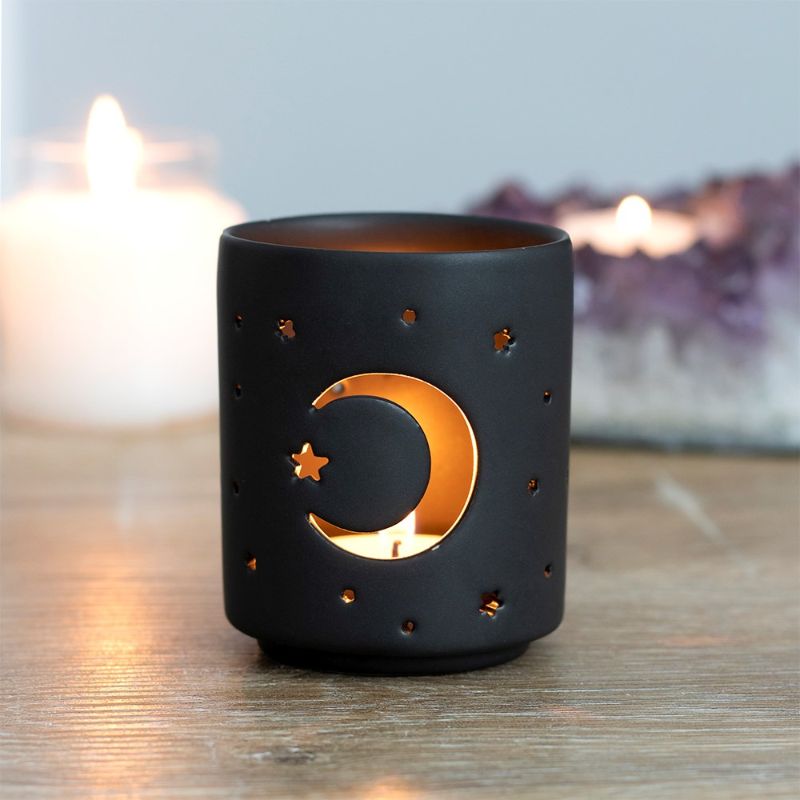 Small black ceramic tealight holder with mystical moon and star cut-outs, perfect for creating a cozy ambiance.