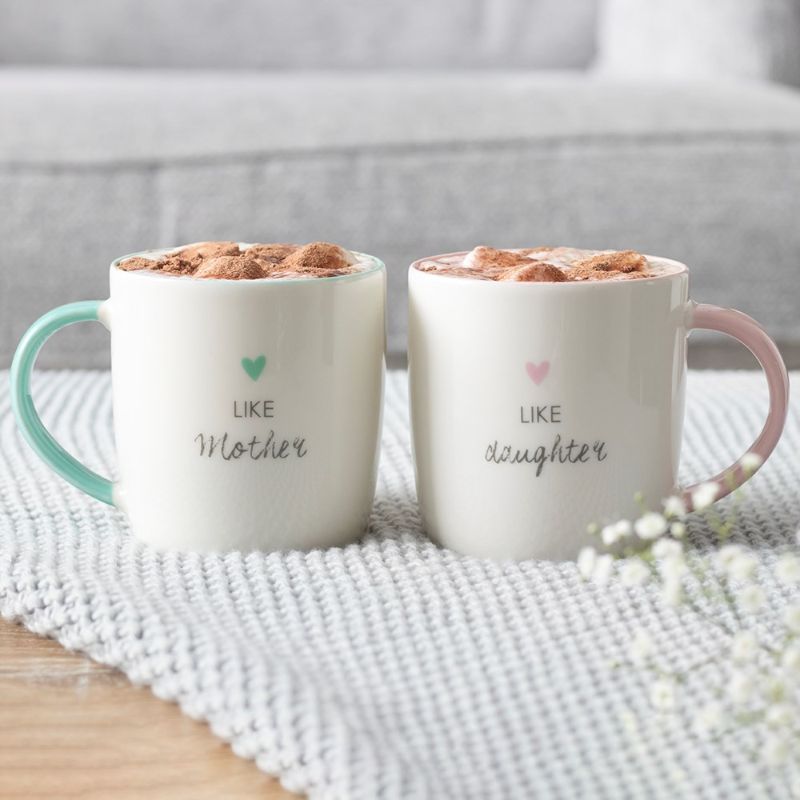 A charming double mug set in pastel teal and pink, celebrating the bond between mothers and daughters with heartfelt inscriptions.