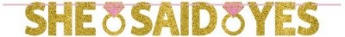 Glittered gold and pink ribbon banner reading "She Said Yes," ideal for engagement celebrations and bridal showers.