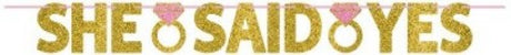 Glittered gold and pink ribbon banner reading "She Said Yes," ideal for engagement celebrations and bridal showers.