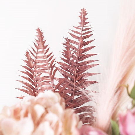Dusty pink artificial fern spray measuring 54cmH, perfect for adding whimsy and elegance to any decor.