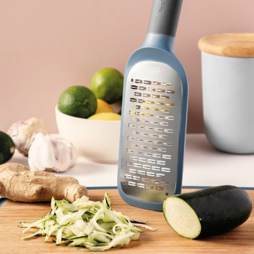 Double-sided paddle grater with sharp stainless steel blades, ergonomic handle, and non-slip base for versatile food prep.