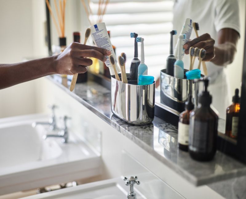 Stylish stainless steel toothbrush caddy with divider for organized storage of brushes and toothpaste, easy to clean.