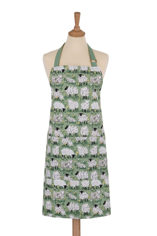 Cotton apron featuring hand-illustrated sheep and lambs against a green countryside backdrop, made from sustainable materials.