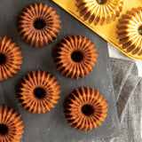 Nordic Ware Brilliance Bundtlette Pan for baking six mini Bundt cakes, featuring durable cast aluminum and nonstick coating.