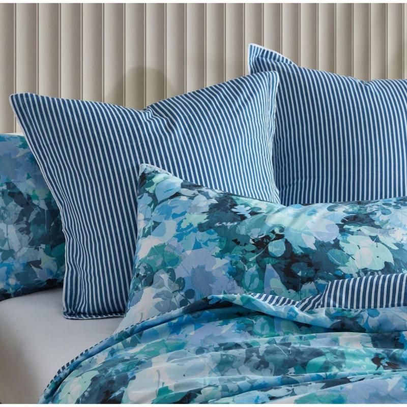 Heather blue European pillowcase with foliage design, navy stripe reverse, and white piping for a stylish bedroom accent.