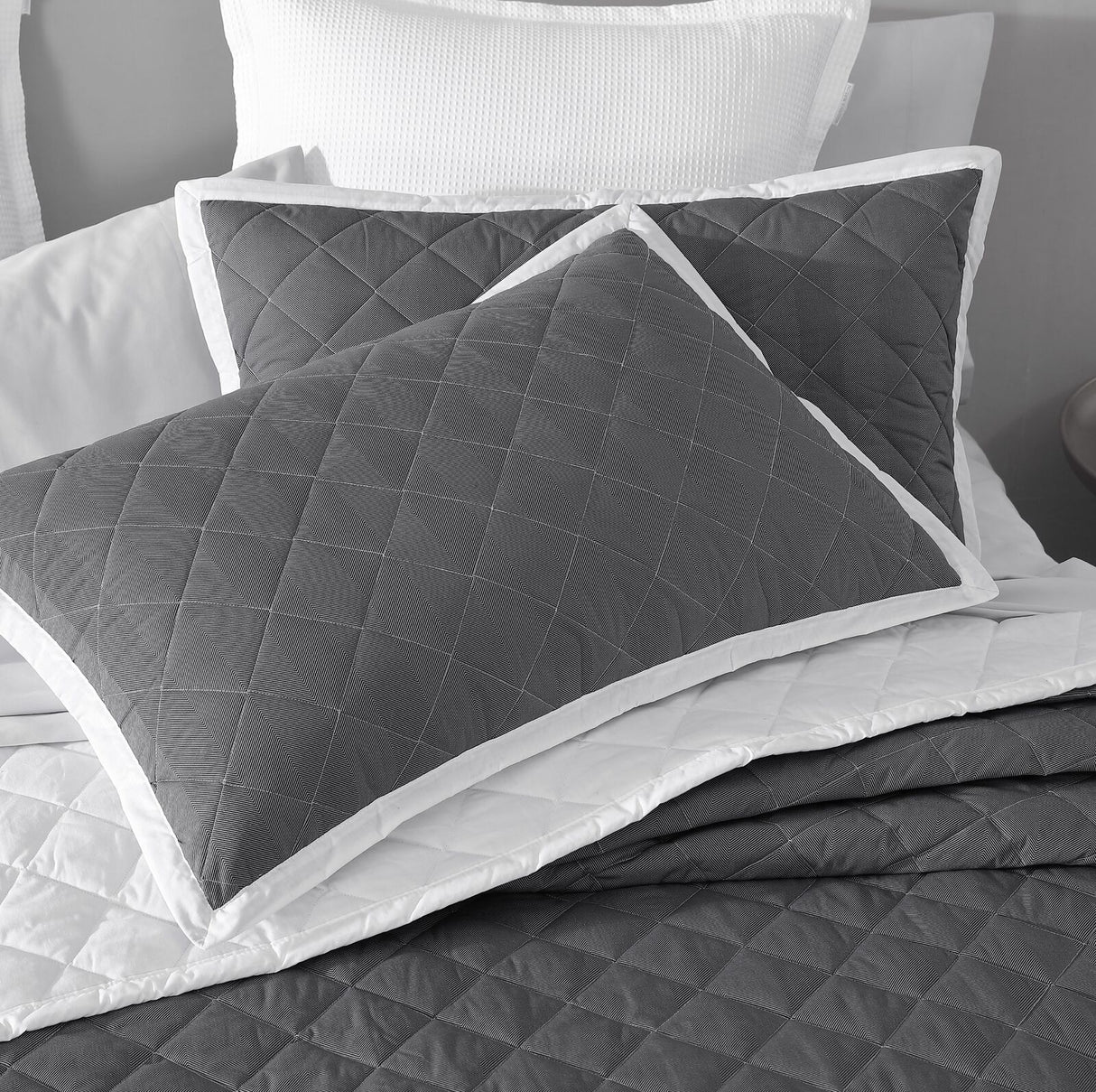 Luxurious quilted pillowcase sham pair in Essex Charcoal, featuring a crisp white bound edge for an elegant bedroom upgrade.