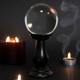 Clear small crystal ball on a sleek black wooden stand, perfect for divination and enchanting home decor.