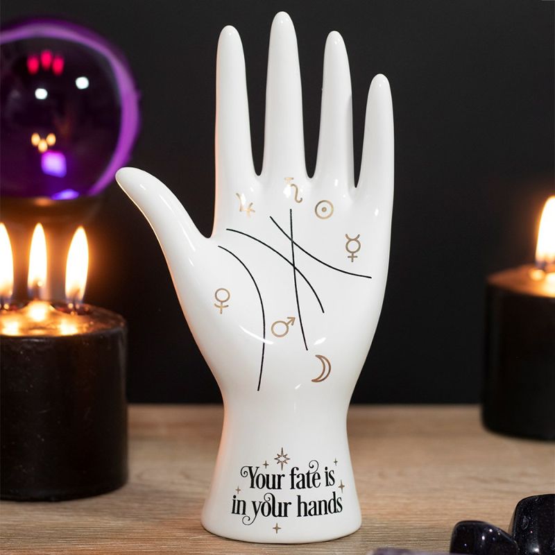 White ceramic palmistry hand ornament with gold astrology symbols and the phrase "Your fate is in your hands," perfect for decor.