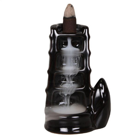 Elegant black ceramic incense burner with split bamboo design, creating cascading smoke for a serene ambiance.