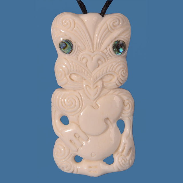 Hand-carved Bone Tiki with Patu pendant on an adjustable cord, featuring Paua shell eyes, symbolizing Maori heritage and protection.