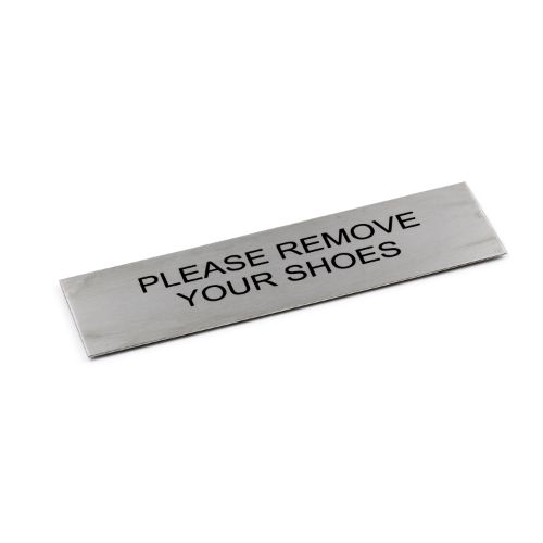 Adhesive black sign "Please Remove Your Shoes," 170 x 50 mm, made of brushed stainless steel for stylish home entryways.