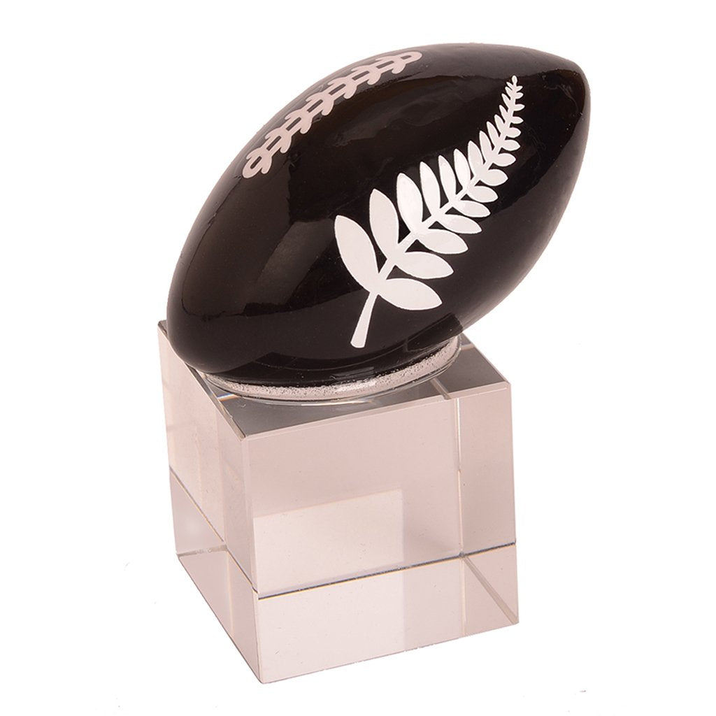 Handcrafted glass rugby ball with silver fern logo on stand, sleek black design, perfect for decor or gifting.