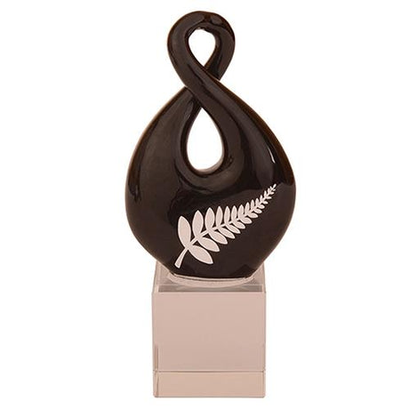 Handmade black glass twist ornament featuring a silver fern logo, symbolizing love and connection.