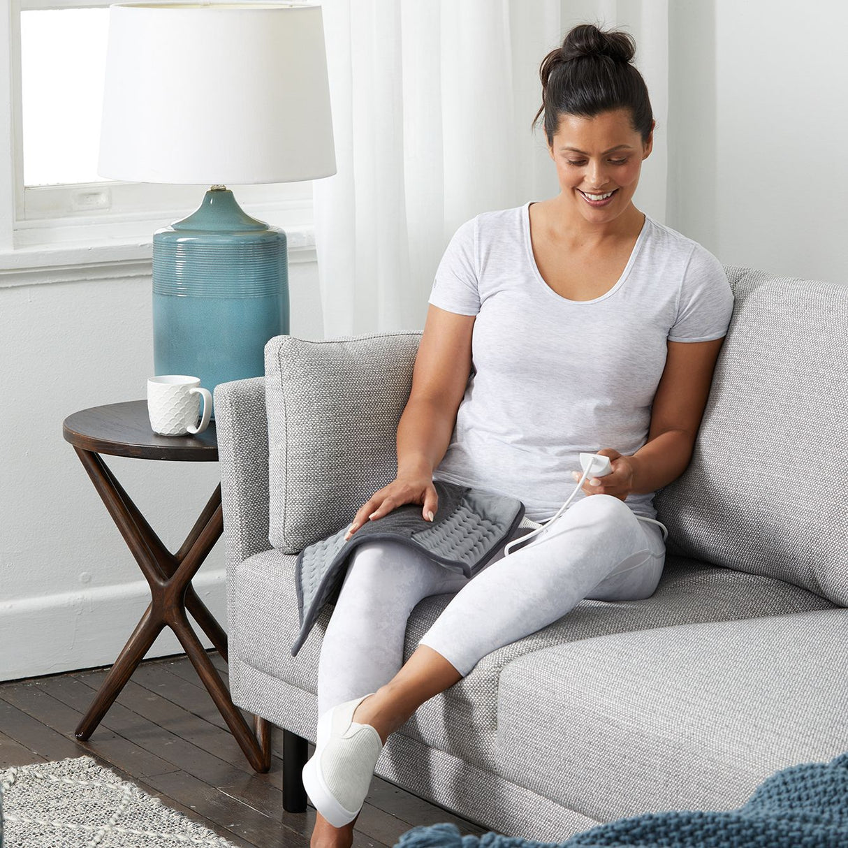 Sunbeam HPM5000 heating pad in grey, featuring rapid heating, 5 settings, and a fabric sleeve for muscle relief and comfort.