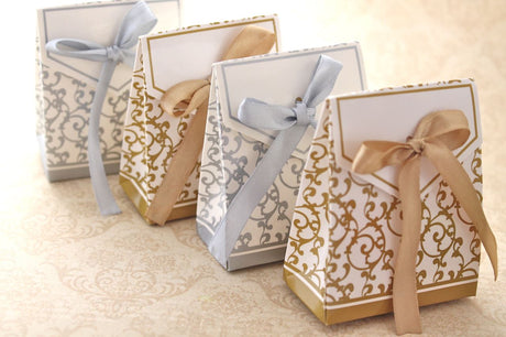 Elegant gold swirl favour boxes (20 units) with ribbons, perfect for weddings and celebrations, measuring 6.7cm x 3.7cm x 8.3cm.