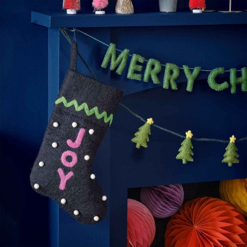 Navy felt Christmas stocking with 'Joy' in pink, green trim, and white snowballs, ideal for festive decor and gifts.