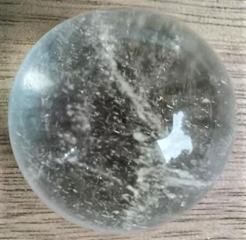 Clear Quartz Crystal Sphere (2CM) enhancing decor and energy, known for clarity and spiritual growth amidst unique natural features.