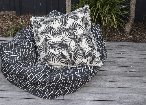 Cushion featuring bold palm print and whimsical fringe in Raven color, perfect for adding tropical charm to any space.