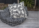 Cushion featuring bold palm print and whimsical fringe in Raven color, perfect for adding tropical charm to any space.