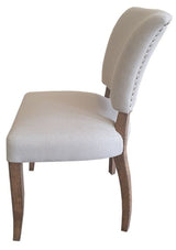Elegant dining chair with natural linen upholstery, oak legs, and brass studs, blending rustic charm with modern luxury.