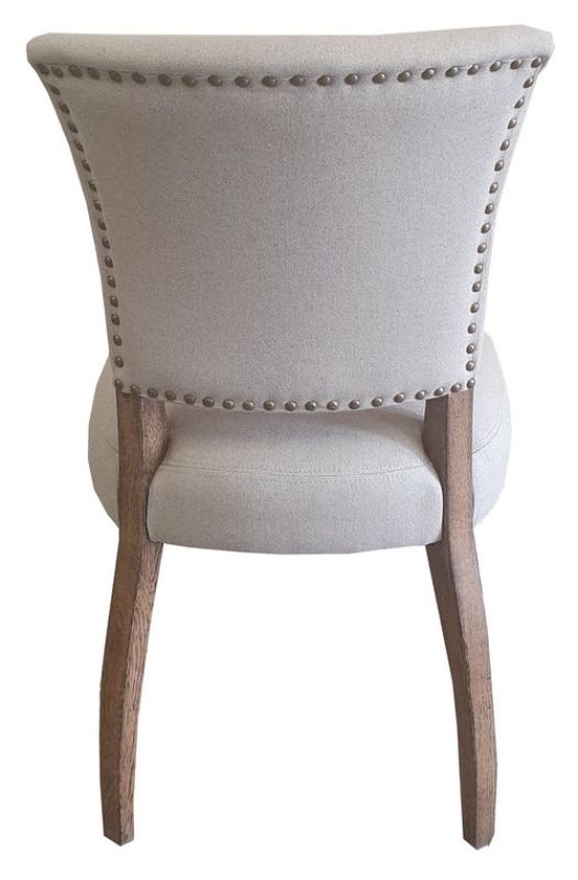 Elegant dining chair with soft linen upholstery, oak legs, and brass studs, combining rustic charm and modern aesthetics.