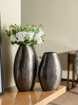 Elegant aluminium vase with vertical chisel design and smoke finish, perfect as a centerpiece for any modern decor.