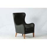 Highback armchair in black leather with olive velvet backrest, featuring brass stud detailing and a solid ash wood frame.