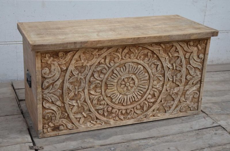 Intricately carved mango wood trunk with iron handles, perfect for stylish storage in any home setting.