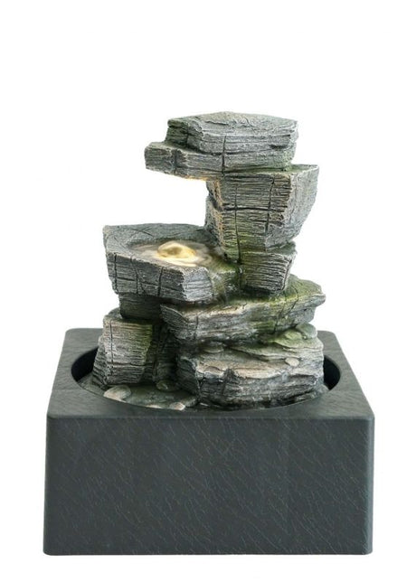 Compact water feature with zen rocks and warm-white light, enhancing tranquility in gardens or interiors.