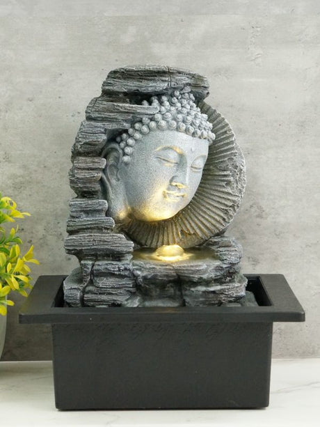 Tranquil Buddha fountain on rock base, 25cm tall, emits soothing water flow and warm white light for serene indoor or garden spaces.