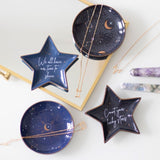 Ceramic blue trinket dish shaped like a crescent moon, adorned with white stars, perfect for holding small treasures.