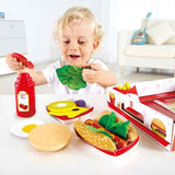 Colorful Hape Fast Food Set featuring a burger, hotdog, fries, and cola for imaginative play and skill development in children.