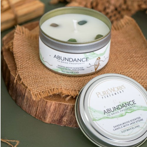 Abundance Sandalwood candle with jade crystal in a decorative tin, promoting tranquility and attracting prosperity.