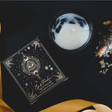 Eye of Providence manifestation candle in black frosted jar, featuring sage and white tea scents with gemstone chips.
