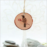 Wood slice ornament featuring intricate filigree tui design, perfect for nature-inspired holiday decor.