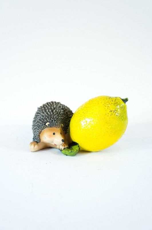 Whimsical mini hedgehog garden ornament holding a vibrant lemon, perfect for adding charm to outdoor spaces.