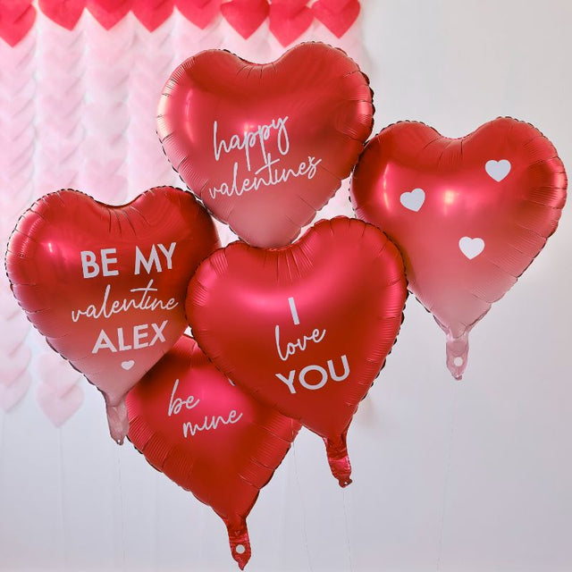 Heart-shaped foil balloons in red and ombré, customizable for Valentine's Day with stickers for personal messages.