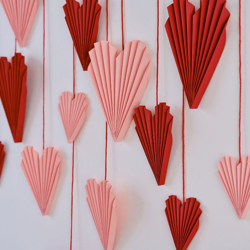 Colorful red and pink palm hearts backdrop for romantic decor, featuring 16 reusable heart decorations and hanging twine.